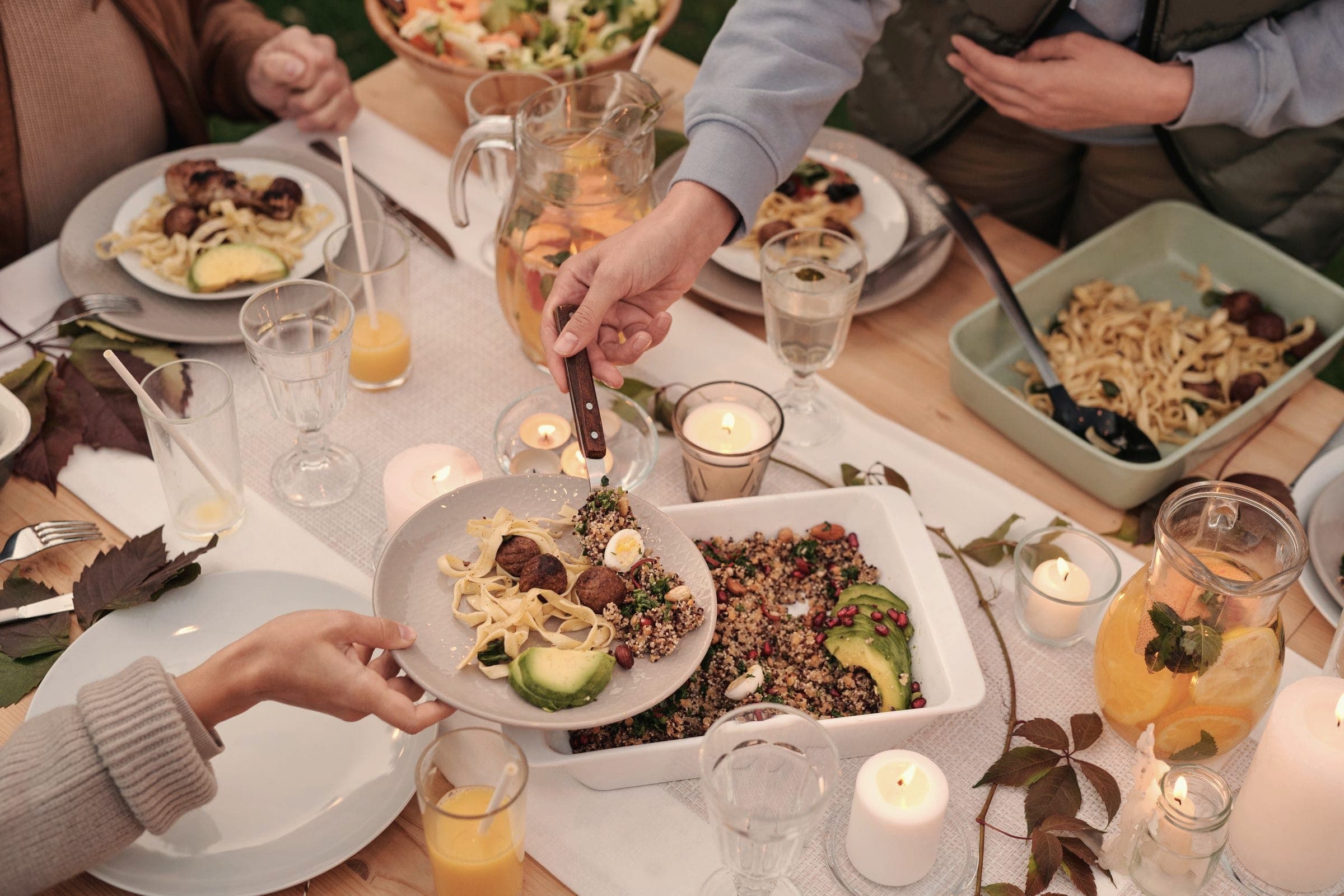 Friends sharing dinner with candles and autumn leaves on the table